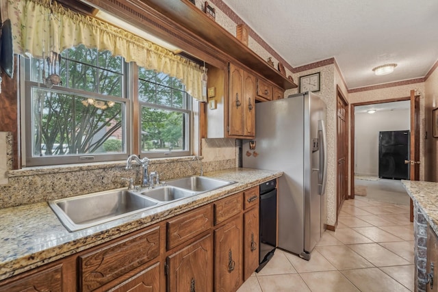 kitchen with brown cabinetry, stainless steel refrigerator with ice dispenser, light countertops, a sink, and light tile patterned floors