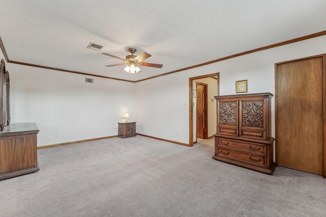 interior space featuring carpet floors, a textured ceiling, baseboards, visible vents, and ornamental molding