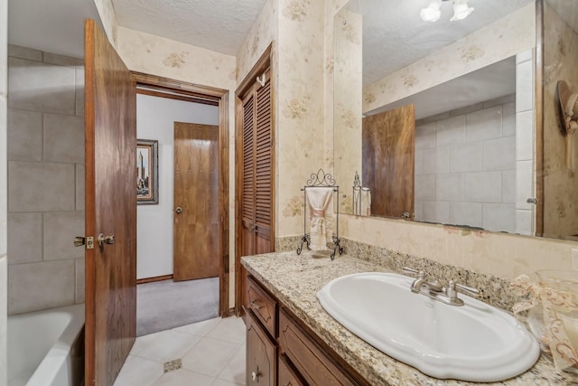 bathroom with vanity, tile patterned flooring, a bathtub, and a textured ceiling