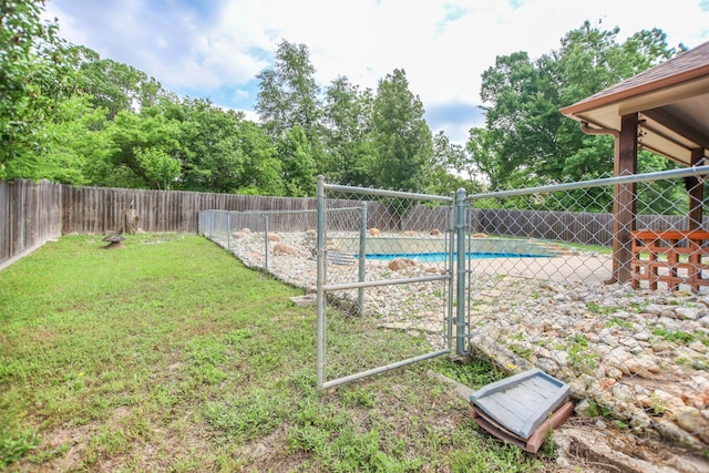 view of yard with a fenced in pool, a fenced backyard, and a gate