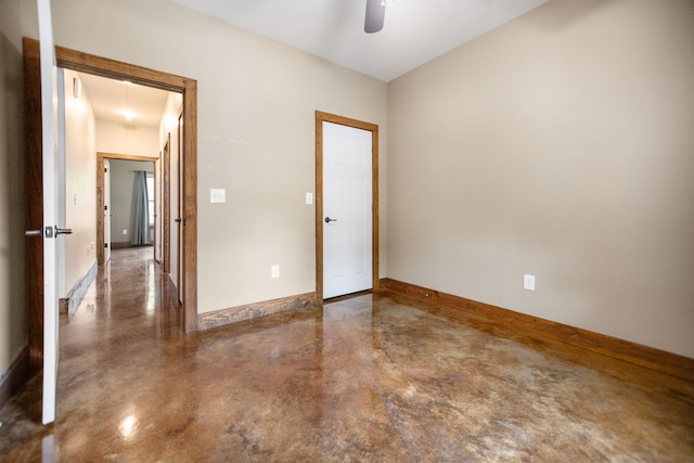 spare room featuring baseboards, ceiling fan, and concrete flooring