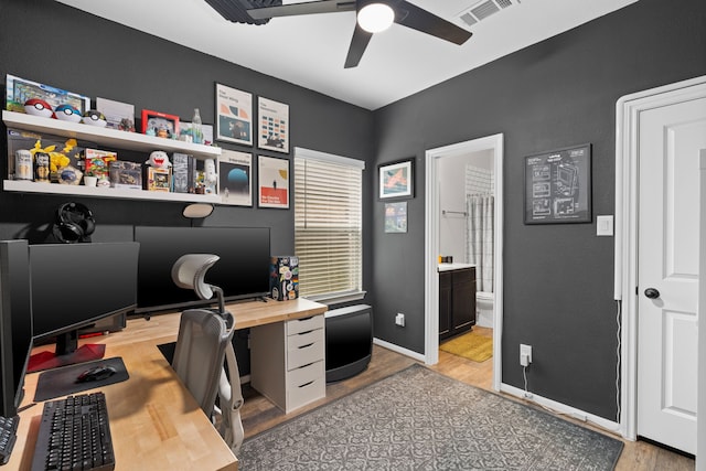 office space with baseboards, a ceiling fan, light wood-type flooring, and visible vents