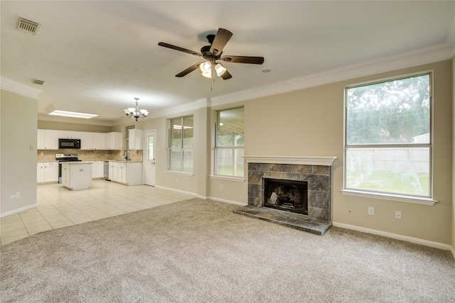 107 Mango St, Lake Jackson, TX 77566 - unfurnished living room featuring light carpet, ceiling fan with notable chandelier, baseboards, visible vents, and ornamental molding