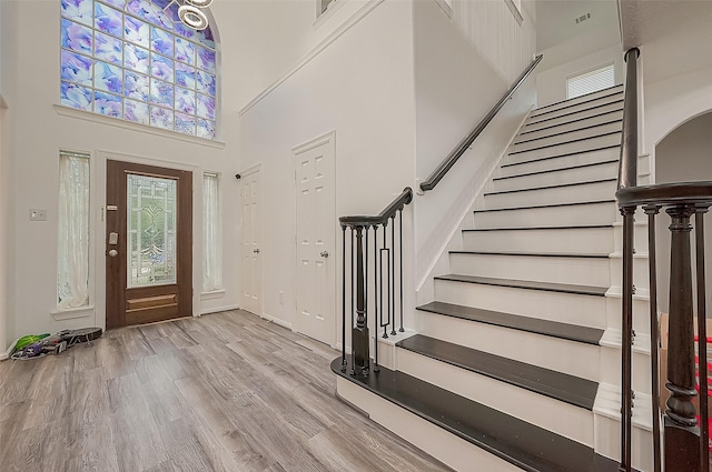 entryway featuring a wealth of natural light, wood finished floors, stairway, and a towering ceiling