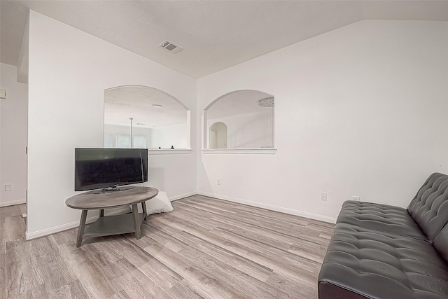 living area with baseboards, lofted ceiling, wood finished floors, and visible vents