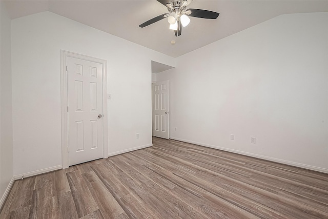spare room with wood finished floors, a ceiling fan, baseboards, and lofted ceiling