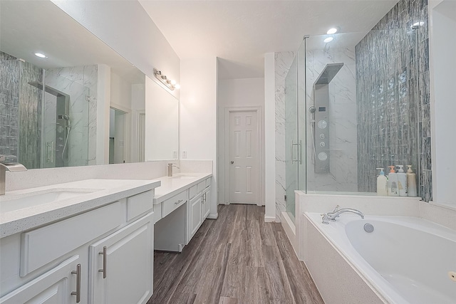 bathroom with a garden tub, a sink, a marble finish shower, and double vanity