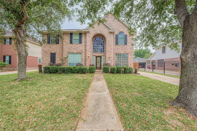 view of front of home with brick siding, fence, french doors, and a front yard