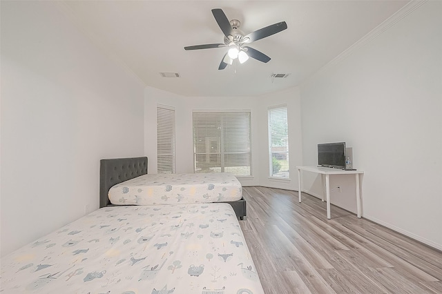 bedroom with ceiling fan, visible vents, ornamental molding, and light wood finished floors