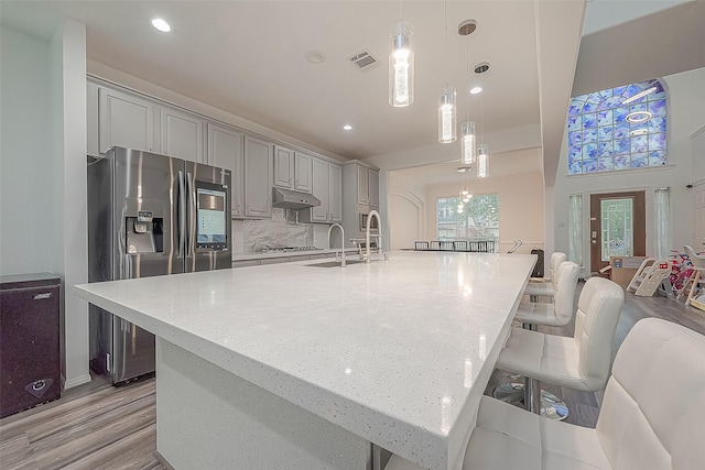kitchen featuring gray cabinets, a kitchen breakfast bar, visible vents, a sink, and stainless steel appliances