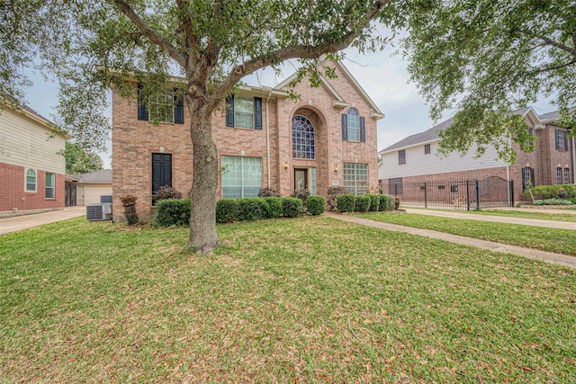 traditional home with fence, central AC unit, brick siding, and a front yard
