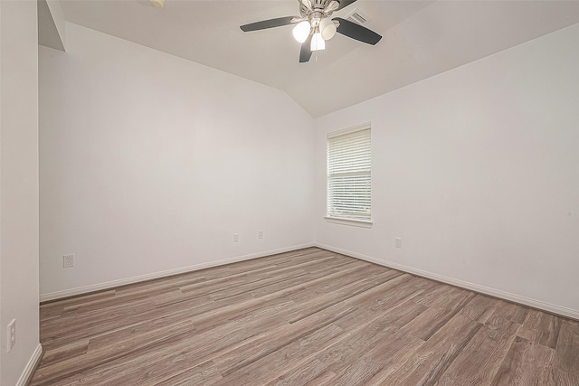 spare room featuring a ceiling fan, visible vents, wood finished floors, baseboards, and lofted ceiling
