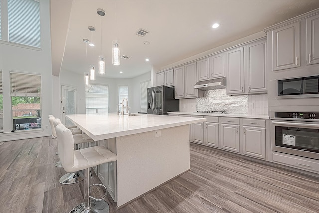 kitchen featuring visible vents, decorative backsplash, light wood-style floors, a sink, and appliances with stainless steel finishes