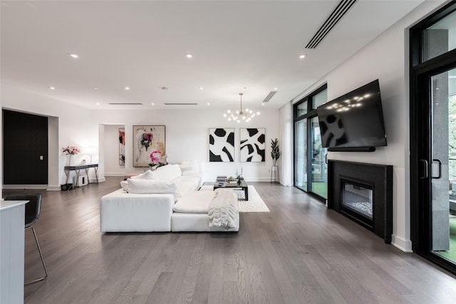 living area with a glass covered fireplace, dark wood finished floors, a chandelier, and visible vents