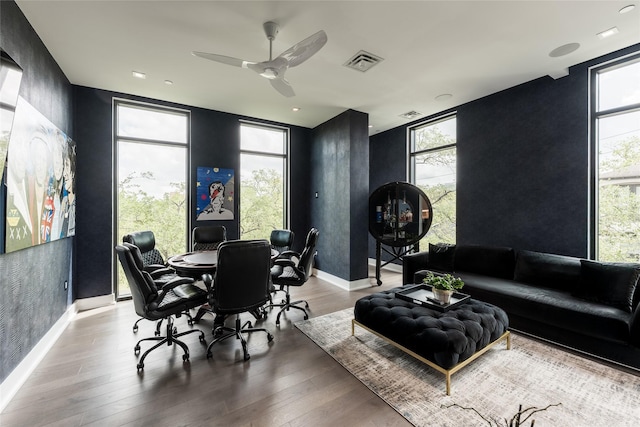 living room featuring a ceiling fan, visible vents, wood finished floors, baseboards, and a wealth of natural light