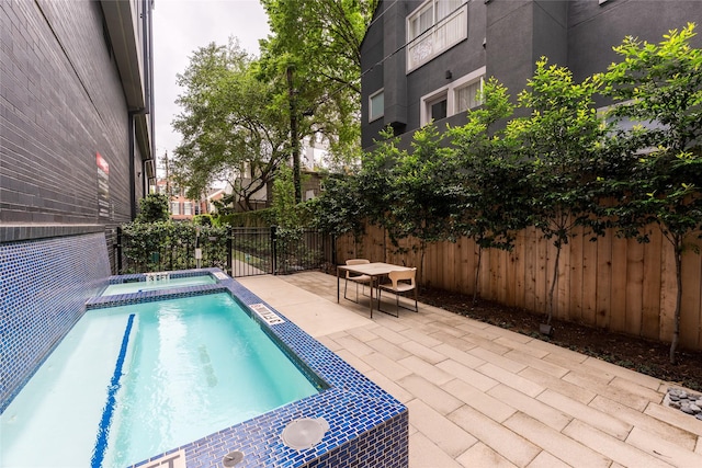 view of swimming pool featuring an in ground hot tub, a fenced in pool, a fenced backyard, and a patio area