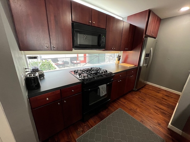 kitchen featuring baseboards, dark wood-style flooring, black appliances, and dark countertops