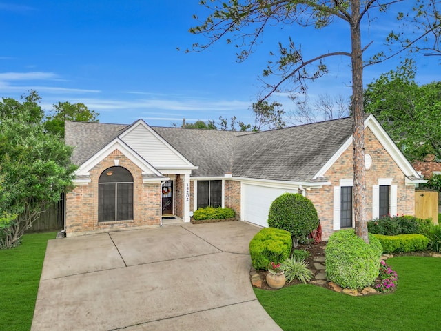 single story home featuring driveway, roof with shingles, brick siding, a front lawn, and an attached garage