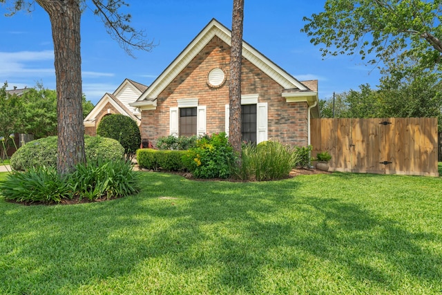 view of property exterior featuring a lawn, brick siding, and fence