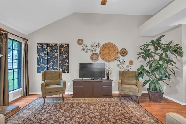 living area with baseboards, wood finished floors, and lofted ceiling