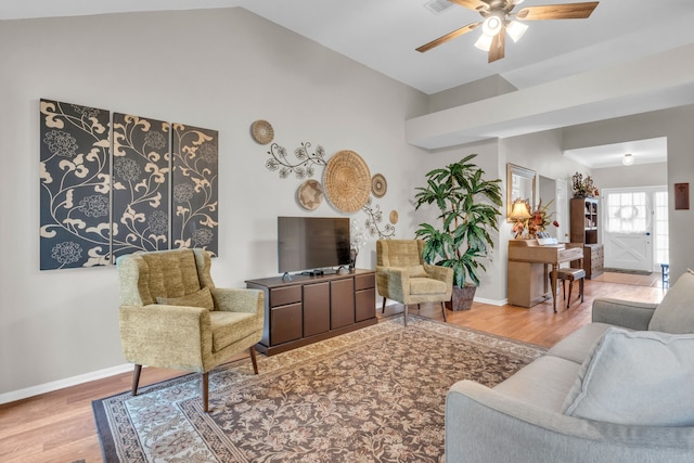 living area with baseboards, ceiling fan, wood finished floors, and vaulted ceiling
