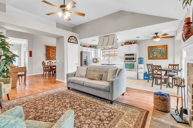 living room with a ceiling fan, light wood finished floors, and lofted ceiling