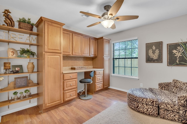 office area featuring built in study area, light wood-style floors, ceiling fan, and baseboards