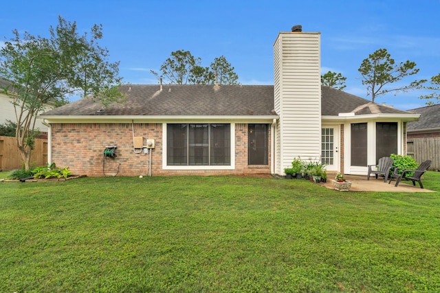 rear view of house featuring fence, a chimney, a lawn, and a patio area
