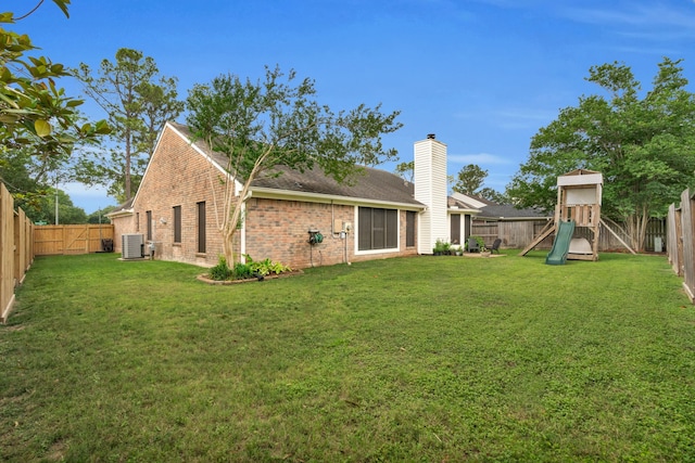 rear view of property with brick siding, a fenced backyard, a playground, and cooling unit
