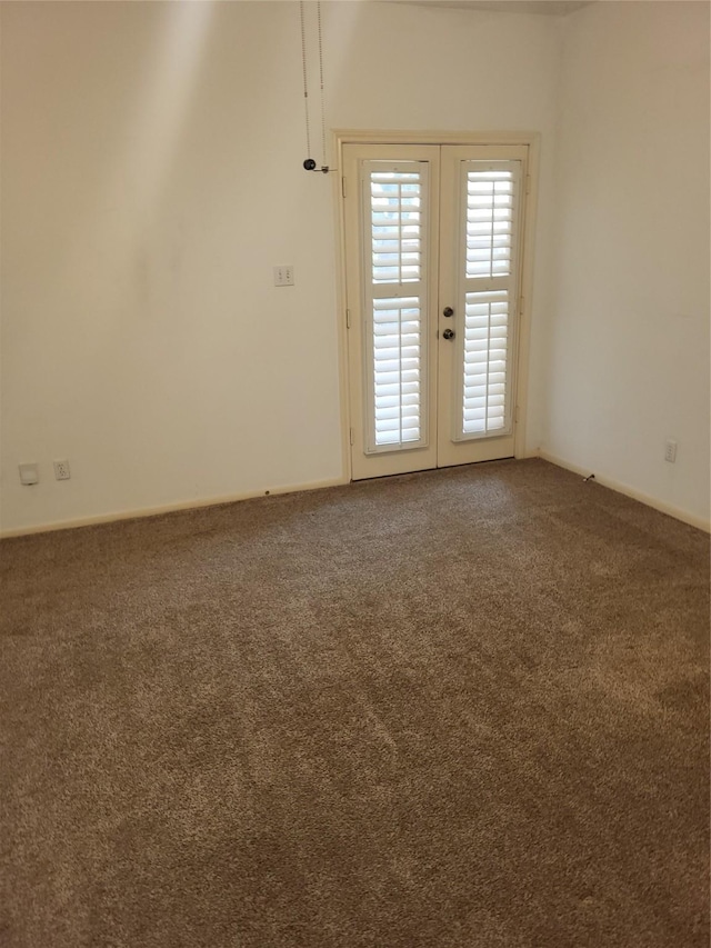 carpeted empty room featuring baseboards and french doors