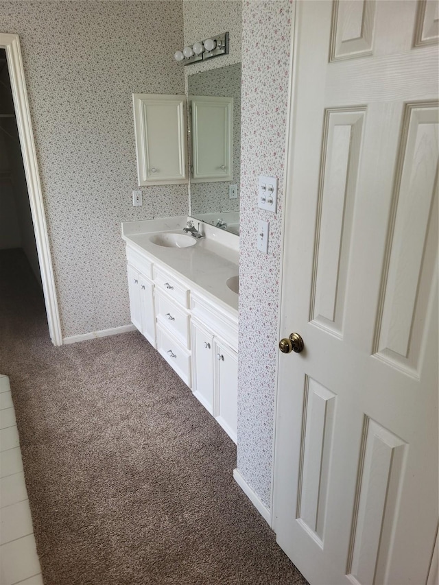 full bath featuring double vanity, a sink, baseboards, and wallpapered walls