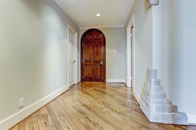 corridor with arched walkways, baseboards, recessed lighting, and wood finished floors