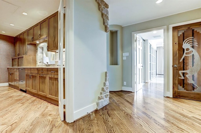 kitchen with baseboards, brown cabinetry, light wood-style floors, and stainless steel dishwasher