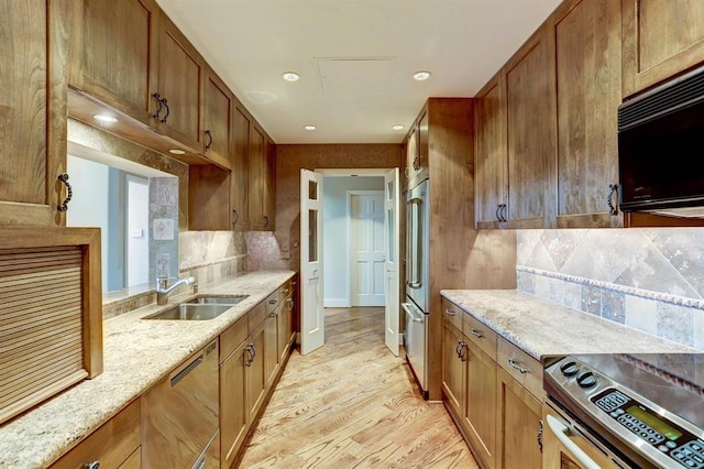 kitchen with a sink, appliances with stainless steel finishes, decorative backsplash, and light wood-type flooring