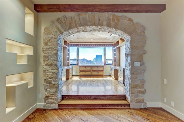 room details featuring baseboards, arched walkways, and wood finished floors