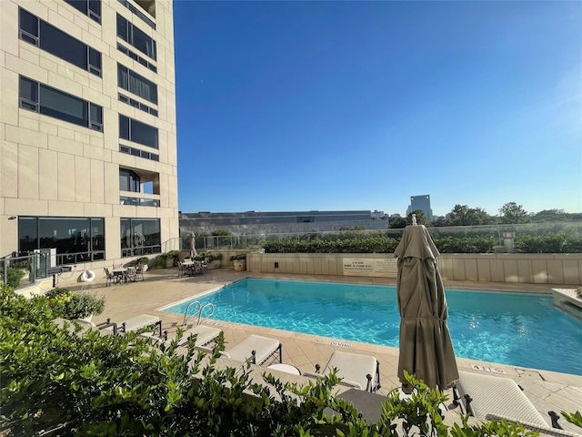 community pool with a patio and fence