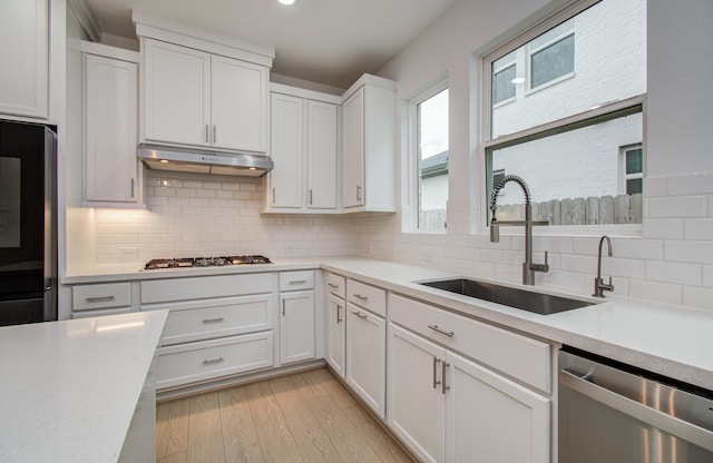 8815 Drysdale River Rd, Cypress, TX 77433 - kitchen with stainless steel dishwasher, gas cooktop, light countertops, under cabinet range hood, and a sink