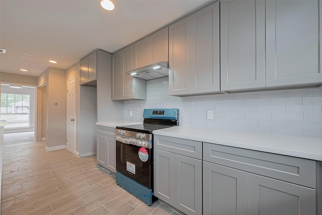 kitchen with gray cabinets, stainless steel electric range, light countertops, baseboards, and under cabinet range hood