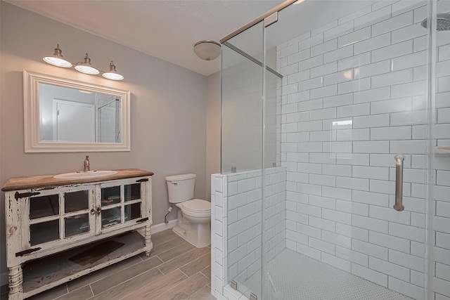 full bathroom featuring toilet, wood finish floors, and a shower stall