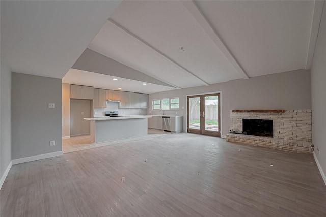 unfurnished living room featuring baseboards, vaulted ceiling with beams, a fireplace, and light wood-style flooring