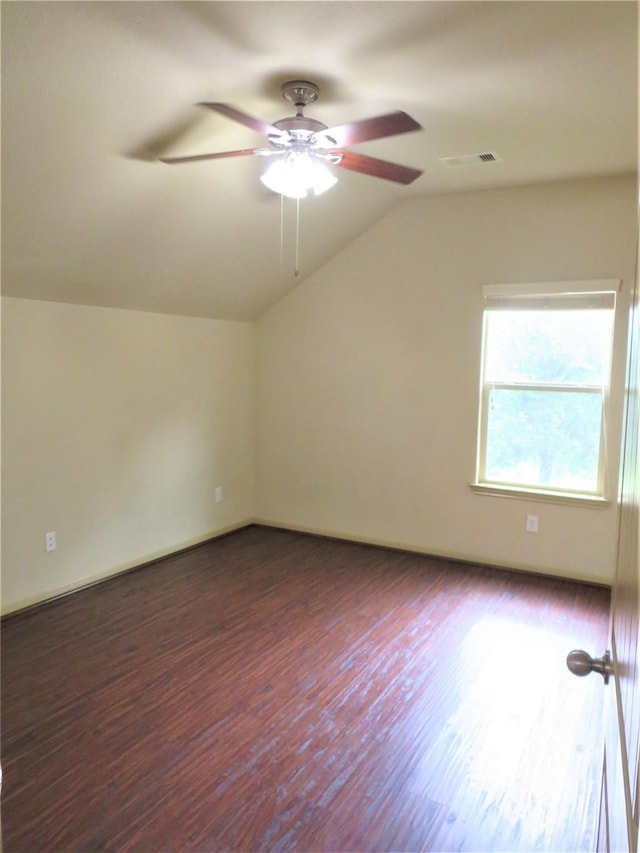 empty room featuring visible vents, lofted ceiling, baseboards, a ceiling fan, and dark wood finished floors