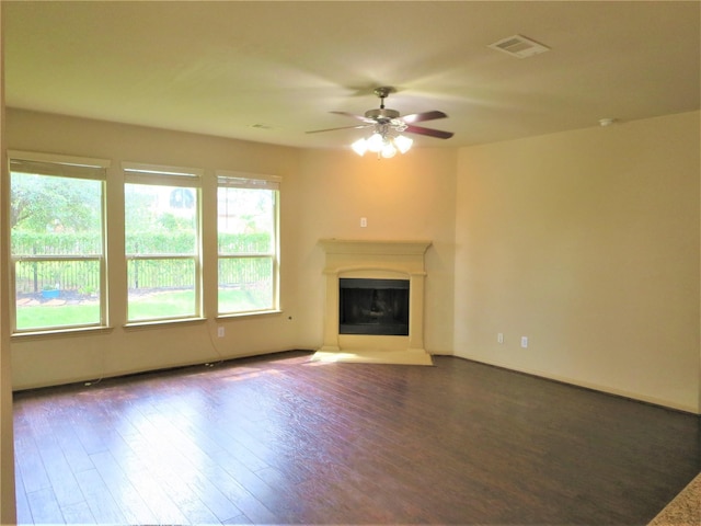 unfurnished living room with a ceiling fan, visible vents, a fireplace with raised hearth, and wood finished floors