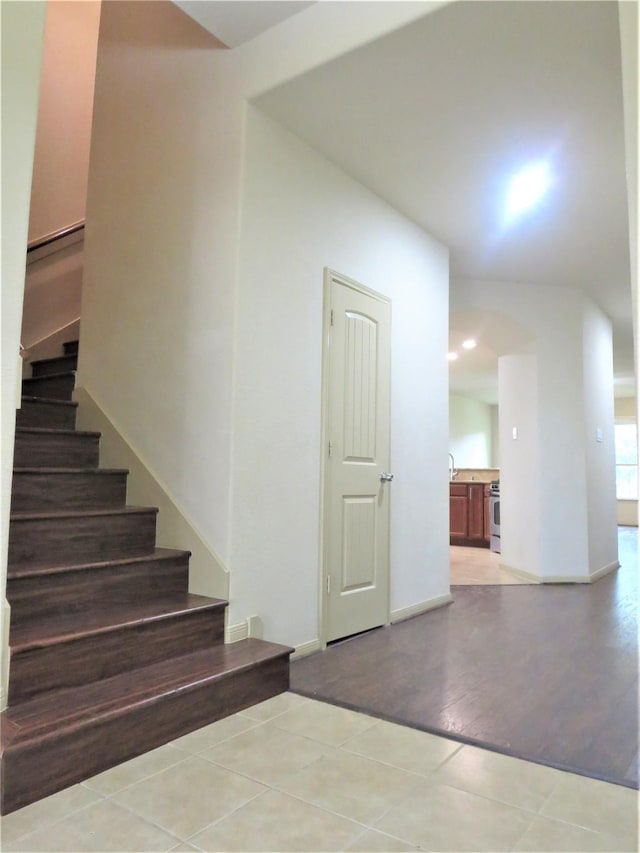 staircase with baseboards, tile patterned flooring, and arched walkways
