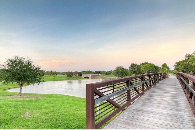view of dock featuring a lawn and a water view