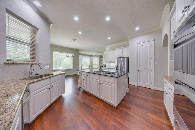 kitchen featuring decorative backsplash, crown molding, appliances with stainless steel finishes, a sink, and recessed lighting
