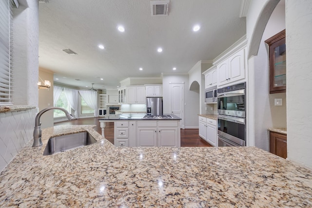 kitchen with a sink, appliances with stainless steel finishes, crown molding, and visible vents