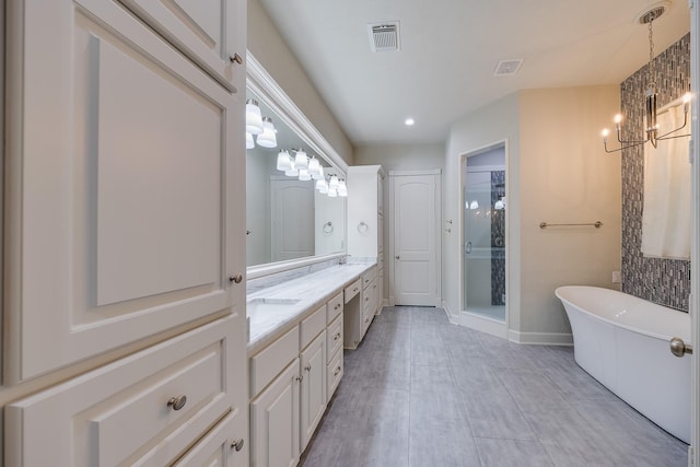 bathroom featuring visible vents, double vanity, a freestanding tub, a stall shower, and a notable chandelier