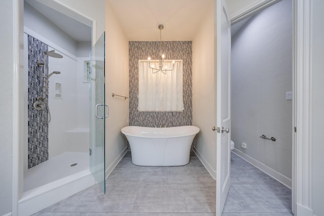 bathroom with tile patterned flooring, a shower stall, toilet, a notable chandelier, and a soaking tub