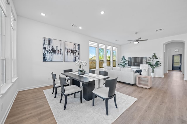 dining area featuring arched walkways, a ceiling fan, visible vents, and light wood-style floors