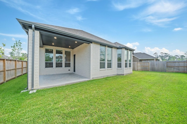 back of property with a fenced backyard, a yard, and a patio area
